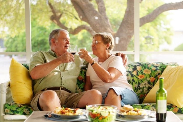 Senior couple smiling on couch outside