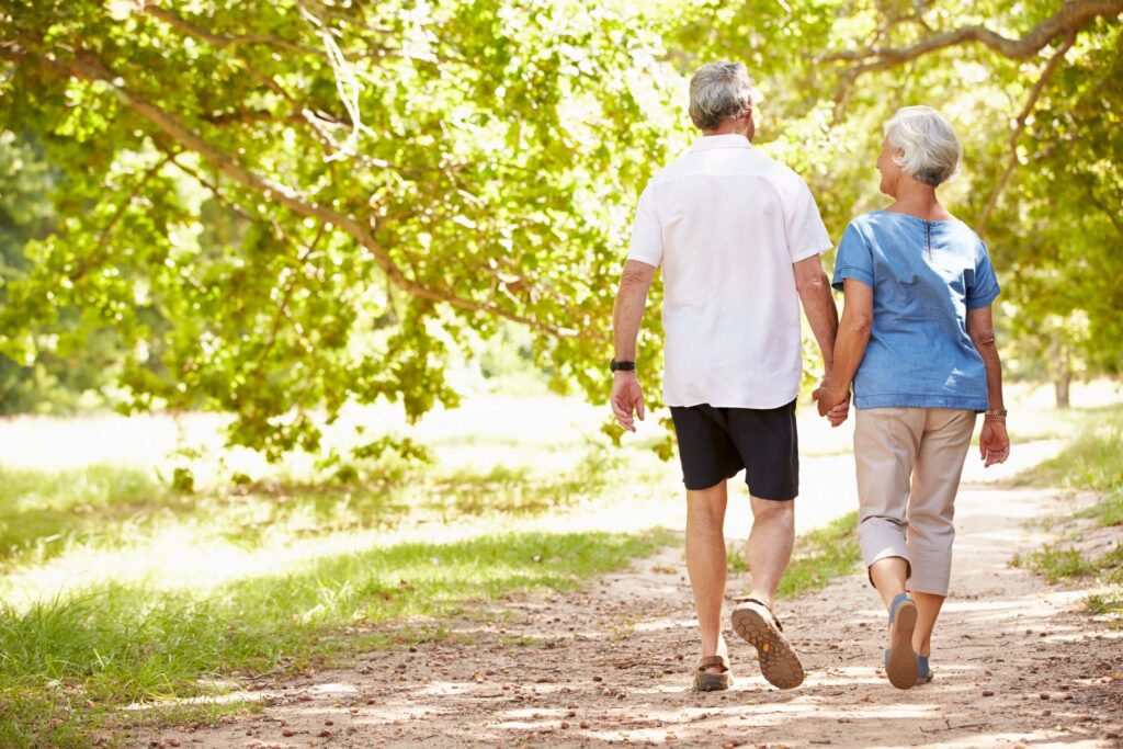 Elderly couple walking down a dirt path.